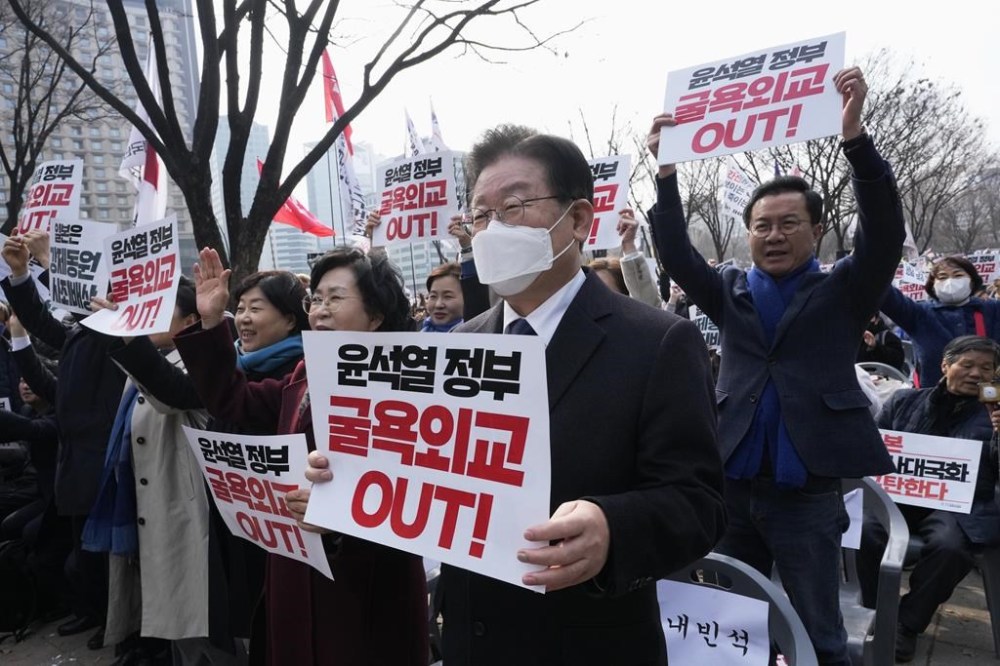 South Korea's main opposition Democratic Party leader Lee Jae-myung, center, holds a banner during a rally against the South Korean government's move to improve relations with Japan in Seoul, South Korea, Wednesday, March 1, 2023. South Korea's president on Wednesday called Japan