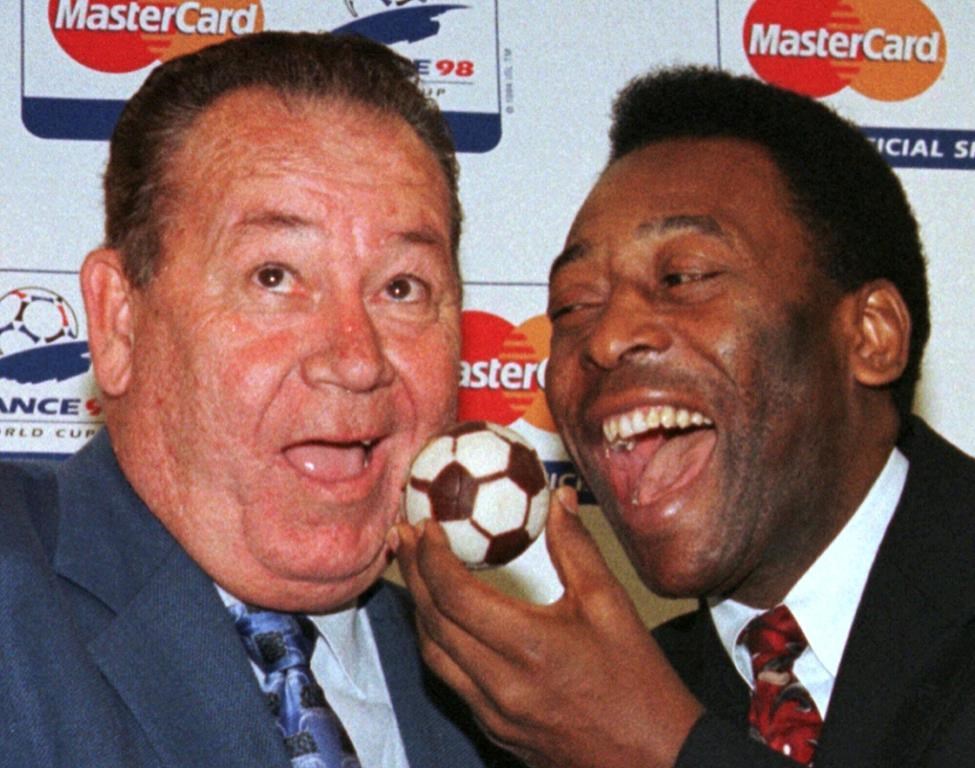 FILE - Soccer legend Pele, of Brazil, feeds French soccer legend Just Fontaine, left, with a soccer ball cake Sunday, July 5, 1998 in Paris.French soccer great Just Fontaine, whose 1958 record of 13 goals scored during a World Cup still stands, has died. He was 89. His former club Reims announced Fontaine's death on Wednesday March 1, 2023. (AP Photo/Jacques Brinon, File)