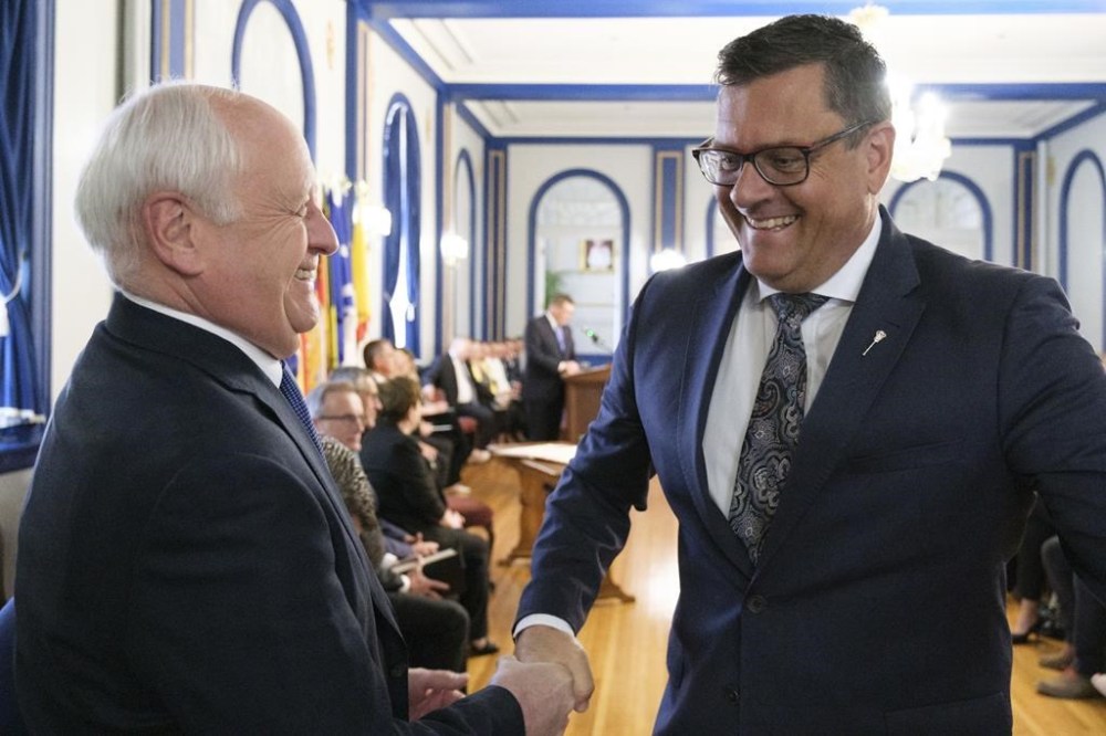 Saskatchewan Agriculture Minister David Marit, left, shakes the hand of Health Minister Paul Merriman, right, at a press conference at Government House in Regina on Tuesday May 31, 2022 as the government announced a cabinet shuffle. THE CANADIAN PRESS/Michael Bell