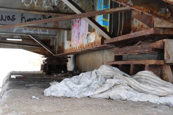 A blanket lies among broken glass and drug-use supplies beneath a bridge in the Point Douglas neighbourhood. (Tyler Searle / Winnipeg Free Press)