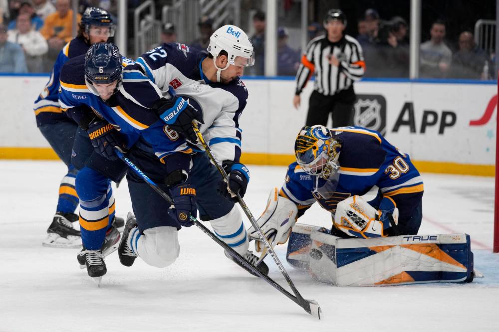 Hofer stops a push as Nino Niederreiter watches and Marco Scandella defends during the first period Sunday. (Jeff Roberson / The Associated Press)
