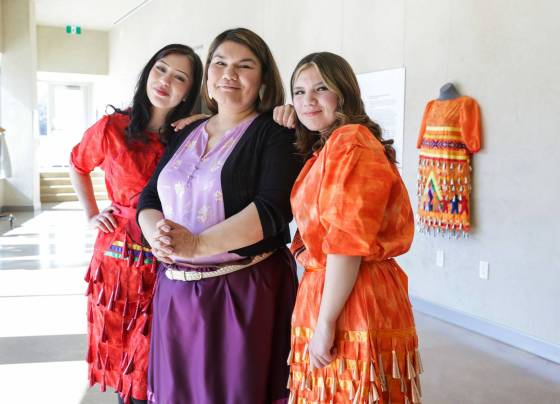 Amanda Grieves with her daughters, Heavenly Ballantyne (left) and Karalyn Braddurn, next to her jingle dress on display at CMHR. (Ruth Bonneville / Winnipeg Free Press)
