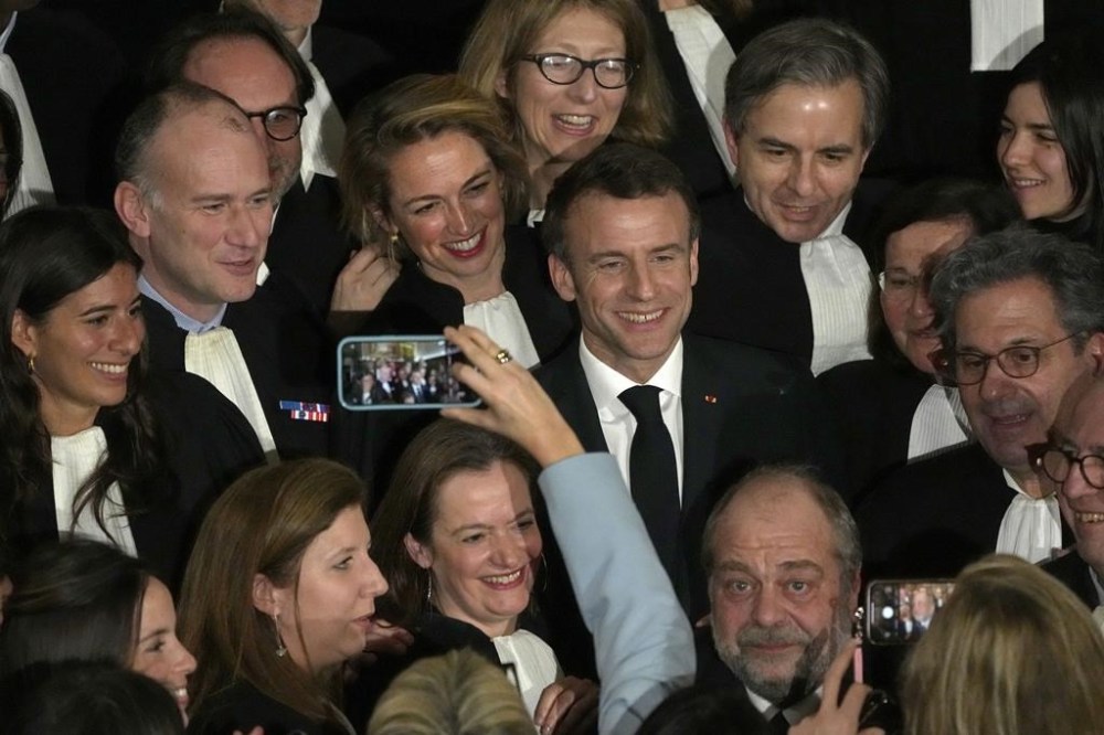 French President Emmanuel Macron, center, with Justice Minister Eric Dupont-Moretti, bottom right, pose with lawyers after delivering a speech paying homage to French feminist figure and lawyer Gisele Halimi at the Appeal Court, Wednesday, March 8, 2023 in Paris. (AP Photo/Michel Euler, Pool)