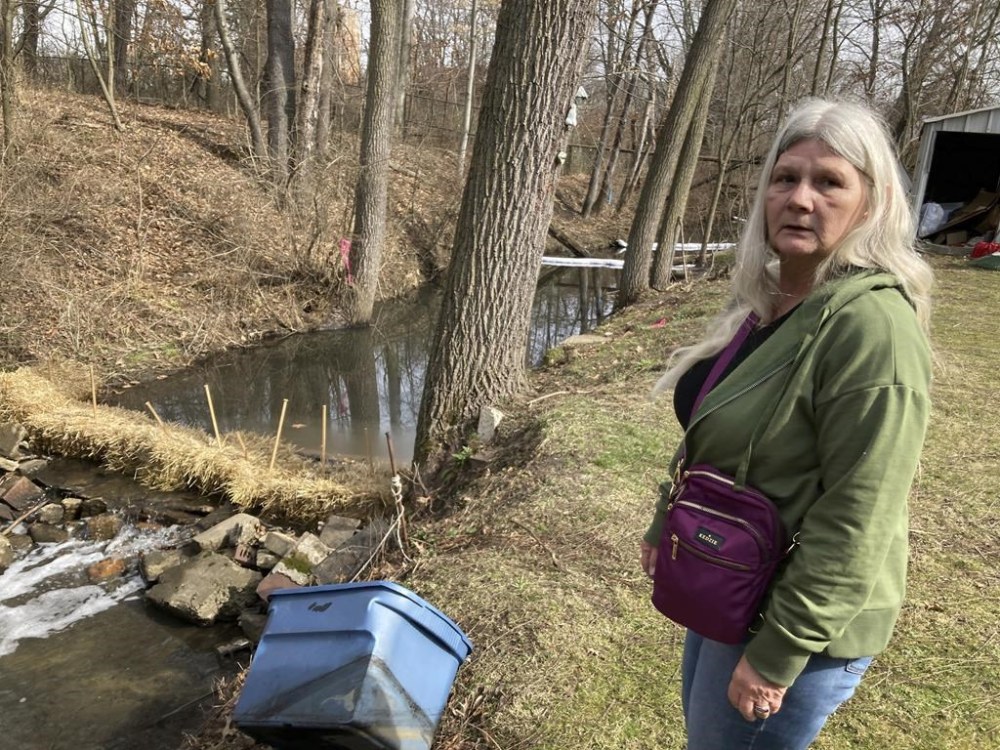 Sherry Bable stands beside Sulphur Run, a creek, Feb. 25, 2023, in East Palestine, Ohio, near the spot where a train derailed in a fiery crash Feb. 3. It's among local waterways where