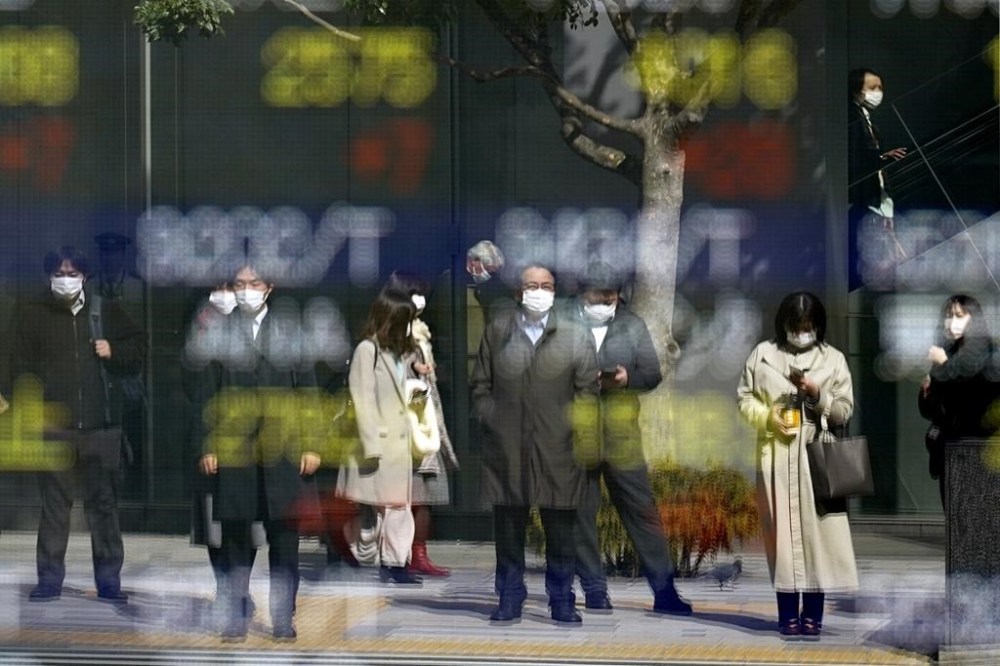 FILE - People are reflected on a glass window of an electronic stock board showing Japan's Nikkei 225 index at a securities firm on March 3, 2023, in Tokyo. Asian shares mostly fell Monday, March 13, shaken by a Wall Street tumble that set off worries the biggest U.S. bank failure in nearly 15 years might have ripple effects around the world. (AP Photo/Eugene Hoshiko, File)