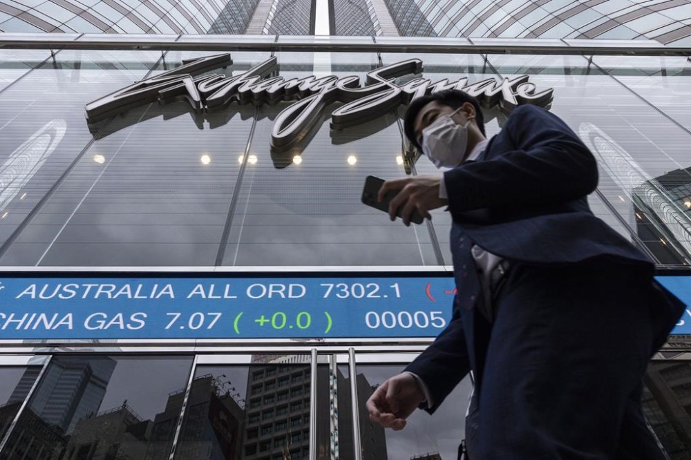 A pedestrian passes by the Hong Kong Stock Exchange electronic screen in Hong Kong on Monday, March 13, 2023. Asian shares mostly fell Monday, shaken by a Wall Street tumble that set off worries the biggest U.S. bank failure in nearly 15 years might have ripple effects around the world. (AP Photo/Louise Delmotte)