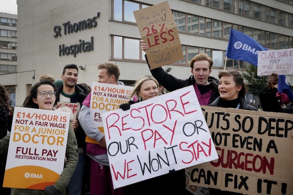 Junior doctors hold placards as they stand at a picket line outside St Thomas' Hospital in Westminster, London, Monday, March 13, 2023. Thousands of junior hospital doctors are due to walk out for three days starting Monday. It follows strikes in recent months by nurses and ambulance staff. The NHS said it would prioritize emergency care during the strike but thousands of appointments will be canceled. (AP Photo/Kirsty Wigglesworth)