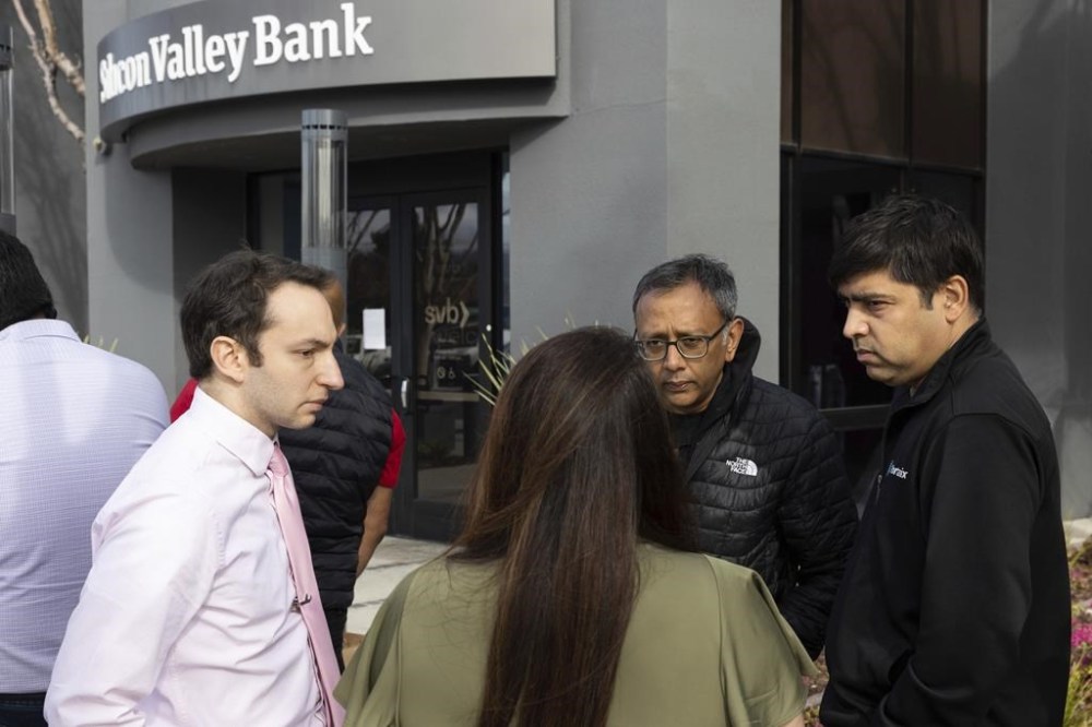 Igor Fayermark, left, from the Federal Deposit Insurance Corporation (FDIC), speaks with customers at Silicon Valley Bank's headquarters in Santa Clara, Calif., on Monday, March 13, 2023. The federal government intervened Sunday to secure funds for depositors to withdraw from Silicon Valley Bank after the banks collapse. Dozens of individuals waited in line outside the bank to withdraw funds. (AP Photo/Benjamin Fanjoy)