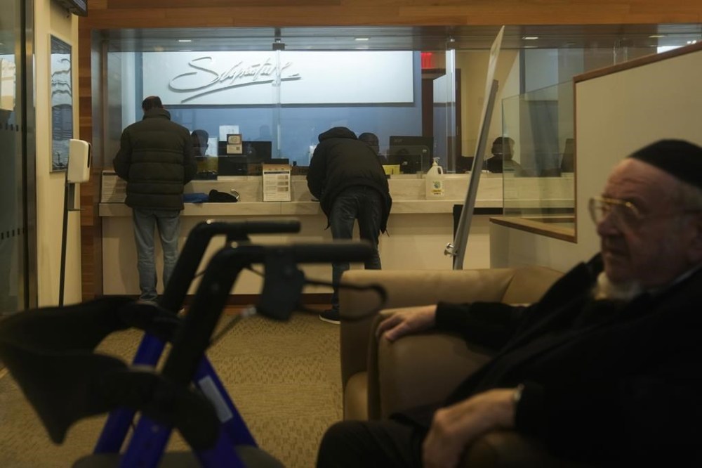 Customers do business at a branch of Signature Bank in New York, Monday, March 13, 2023. President Joe Biden is telling Americans that the nation's financial systems are sound. This comes after the swift and stunning collapse of two banks that prompted fears of a broader upheaval. (AP Photo/Seth Wenig)