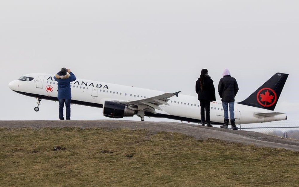 People look on as an Air Canada plane takes off from Montreal Trudeau Airport in Montreal, Sunday, Dec. 5, 2021. The Air Canada Pilots Association says it has reached an agreement in principle on a possible merger with the Air Line Pilots Association -- the largest airline pilot union in the world. THE CANADIAN PRESS/Graham Hughes