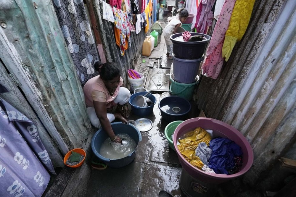 A woman washes utensils outside her house in a slum area on the eve of World Water Day in Mumbai, India, Tuesday, March 21, 2023. (AP Photo/Rajanish Kakade)
