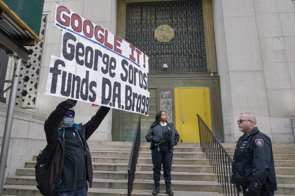 Court officers and a demonstrator, left, stand outside the building the Grand Jury meets, Wednesday, March 22, 2023, in New York. A New York grand jury investigating Trump over a hush money payment to a porn star appears poised to complete its work soon as law enforcement officials make preparations for possible unrest in the event of an indictment. (AP Photo/Mary Altaffer)
