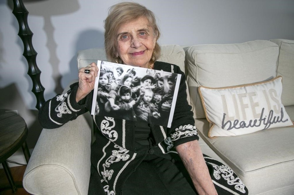 In Morristown, New Jersey, on Monday, March 13, 2023, Holocaust survivor Tova Friedman, 85, holds out her left arm to show the number the Nazis tattooed while holding a photo of her as a six-year-old on the left in the picture, holding out the same arm to show the tattoo to the camera in 1945 after the Soviet military liberated Auschwitz concentration camp. To combat anti-semitism, Friedman's grandson, 17-year-old Aron Goodman, records TikTok videos of her describing the Holocaust that have millions of views on the social media platform. (AP Photo/Ted Shaffrey)