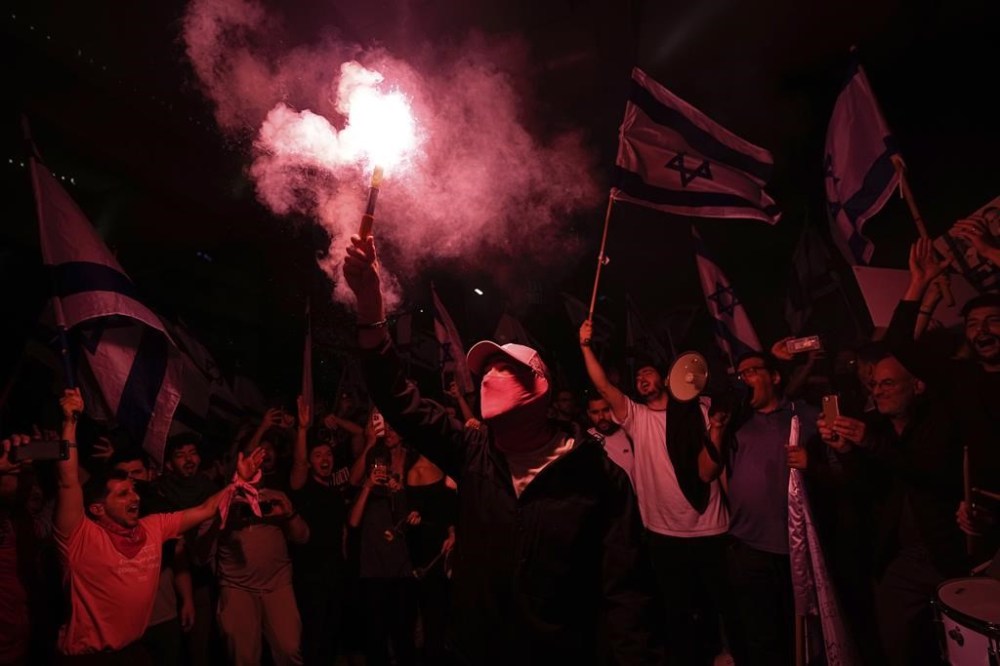 Israelis opposed to Prime Minister Benjamin Netanyahu's judicial overhaul plan block a highway during a protest after the Israeli leader fired his defense minister, in Tel Aviv, Israel, Monday, March 27, 2023. Defense Minister Yoav Gallant had called on Netanyahu to freeze the plan, citing deep divisions in the country and turmoil in the military. (AP Photo/Ohad Zwigenberg)