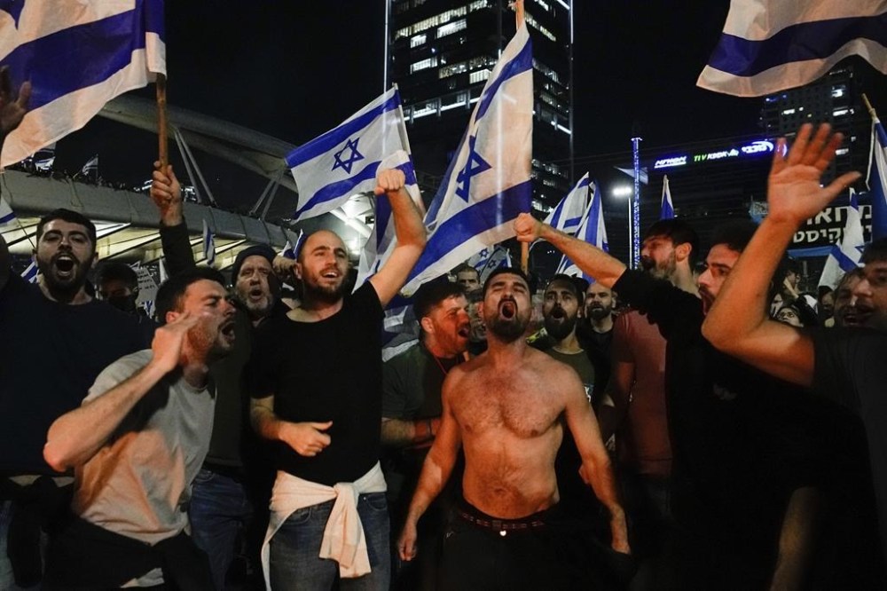 Israelis opposed to Prime Minister Benjamin Netanyahu's judicial overhaul plan block a highway during a protest moments after the Israeli leader fired his defense minister, in Tel Aviv, Israel, Sunday, March 26, 2023. Defense Minister Yoav Gallant had called on Netanyahu to freeze the plan, citing deep divisions in the country and turmoil in the military. (AP Photo/Ohad Zwigenberg)
