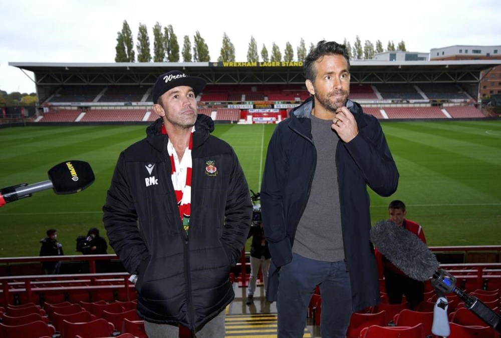 FILE - Wrexham co-chairmen Rob McElhenney, left, and Ryan Reynolds during a press conference at the Racecourse Ground, Wrexham, Wales, on Oct. 28, 2021. Soccer sensation Wrexham AFC is coming to America. The fifth-tier Welsh side, which has become a global fan favorite since Hollywood stars Reynolds and McElhenney bought it and then launched a documentary series,