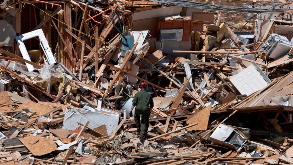 FILE - Tuscaloosa Fire Lt. Brian Phillips climbs a pile of rubble in search of survivors or bodies at an apartment building in Tuscaloosa, Ala., May 4, 2011. Meteorologists are warning of a series of severe storms that could rip across America’s Midwest and South over the next couple of weeks. One weather expert said the current persistent pattern of storm ingredients is consistent with the April 2011 tornado onslaught, one of the largest, deadliest and most destructive tornado outbreaks in American history. (AP Photo/Dave Martin, File)