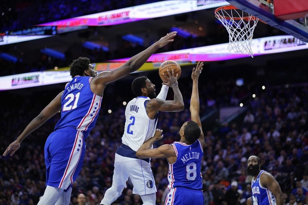 Dallas Mavericks' Kyrie Irving (2) goes up for a shot between Philadelphia 76ers' Joel Embiid (21) and De'Anthony Melton (8) during the first half of an NBA basketball game, Wednesday, March 29, 2023, in Philadelphia. (AP Photo/Matt Slocum)