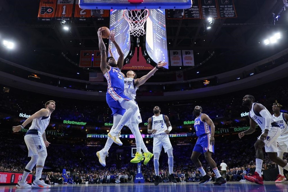 Philadelphia 76ers' Joel Embiid (21) goes up for a dunk against Dallas Mavericks' Dwight Powell (7) during the first half of an NBA basketball game, Wednesday, March 29, 2023, in Philadelphia. (AP Photo/Matt Slocum)