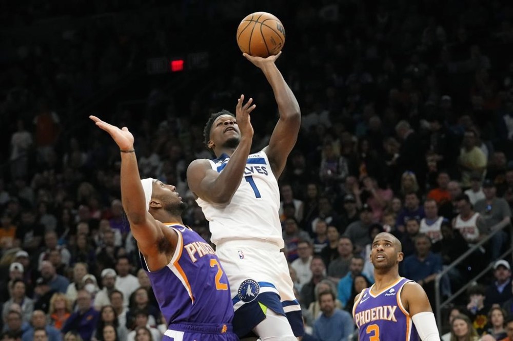 Minnesota Timberwolves guard Anthony Edwards (1) drives past Phoenix Suns forward Josh Okogie (2) as Suns guard Chris Paul, right, looks on during the first half of an NBA basketball game Wednesday, March 29, 2023, in Phoenix. (AP Photo/Ross D. Franklin)
