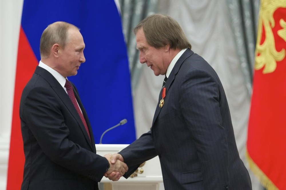 FILE - Russian President Vladimir Putin, left, presents a medal to Russian cellist Sergei Roldugin, during an awarding ceremony in Moscow's Kremlin, Russia, on Thursday, Sept. 22, 2016. Four former bankers with the now-shuttered Swiss affiliate of a major Russian bank have gone on trial over allegations that they didn't properly check accounts opened in the name of a Russian cellist with longtime ties to President Vladimir Putin. (AP Photo/Ivan Sekretarev, Pool, File)