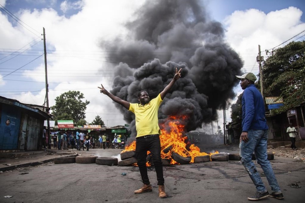 Protesters react next to a burning barricade during a mass rally called by the opposition leader Raila Odinga over the high cost of living, in Kibera Slum, Nairobi, Kenya, Thursday, March 30, 2023. Police in Kenya are on high alert ahead of the third round of anti-government protests organized by the opposition that has been termed as illegal by the government. Police chief Japheth Koome insists that Thursday protests are illegal but the opposition leader Raila Odinga says Kenyans have a right to demonstrate. (AP Photo/Samson Otieno)