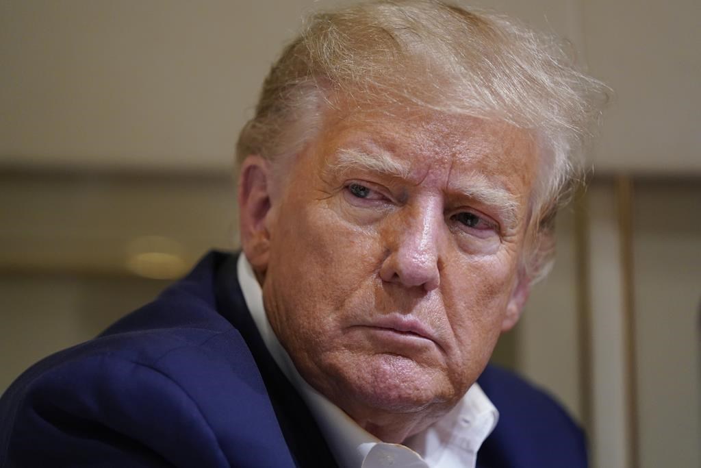 Former president Donald Trump listens as he speaks with reporters while in flight on his plane after a campaign rally at Waco Regional Airport, in Waco, Texas, Saturday, March 25, 2023, while en route to West Palm Beach, Fla. THE CANADIAN PRESS/AP/Evan Vucci