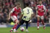 Arsenal's Leandro Trossard and Leeds United's Junior Firpo challenge for the ball during the English Premier League soccer match between Arsenal and Leeds United at the Emirates Stadium in London, Saturday, April 1, 2023.(AP Photo/Kin Cheung)