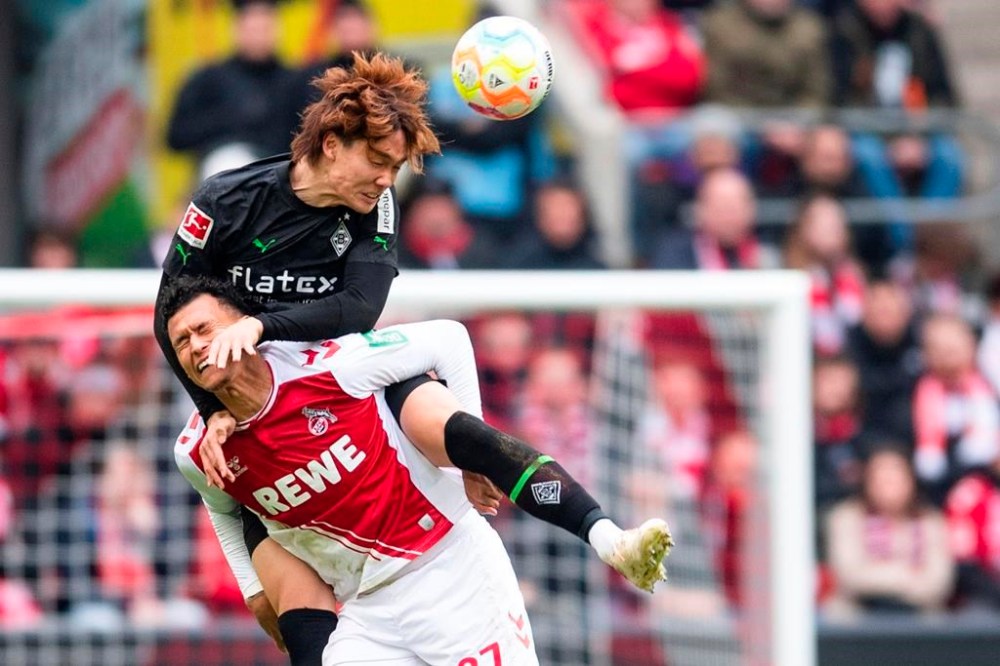 Cologne's Davie Selke, bottom, and Gladbach's Ko Itakura fight for the ball during the German Bundesliga soccer match between Cologne and Borussia Moenchengladbach, at the RehinEnergioStadion in Cologne, Germany, Sunday, April 3, 2023. (Marius Becker/dpa via AP)