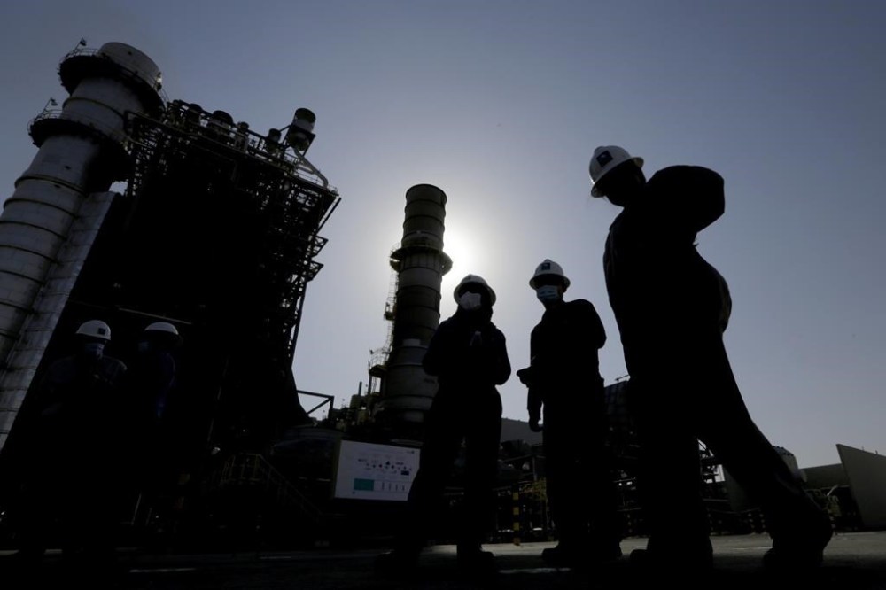 FILE - Saudi Aramco engineers walk in front of a gas turbine generator at Khurais oil field during a tour for journalists, 150 kilometers east-northeast of Riyadh, Saudi Arabia on June 28, 2021. Saudi Arabia said Sunday, April 2, 2023, it will cut oil production by 500,000 barrels per day from May until the end of 2023. (AP Photo/Amr Nabil, File)