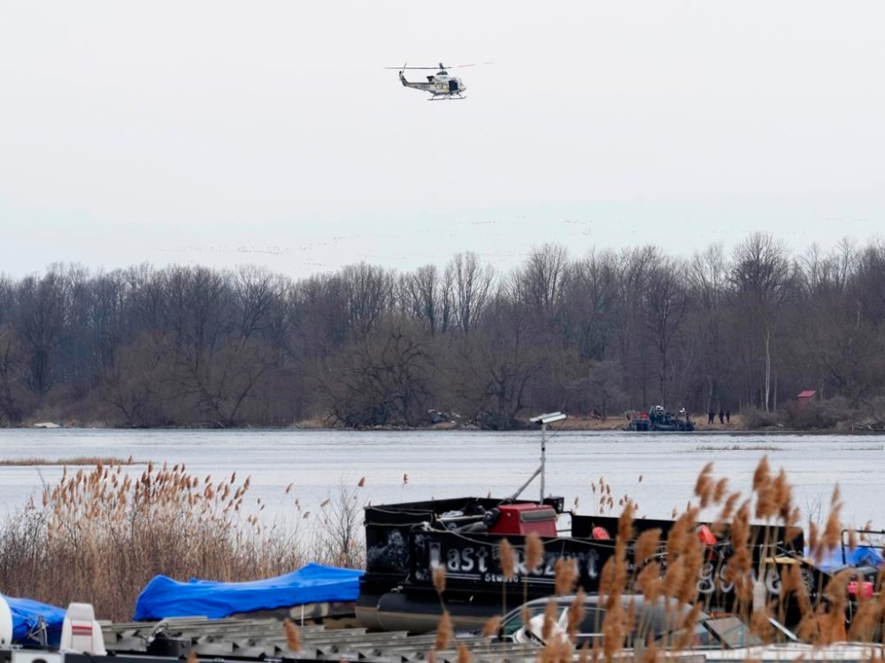 A police helicopter searches the area in Akwesasne, Que., Friday, March 31, 2023. Authorities in the Mohawk Territory of Akwesasne say the bodies of eight migrants of Indian and Romanian descent were pulled from the river Thursday. THE CANADIAN PRESS/Ryan Remiorz