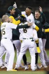 Oakland Athletics' Tony Kemp, center, celebrates with Seth Brown (15) and Jace Peterson (6) after driving in the winning run with a single against the Cleveland Guardians during the ninth inning of a baseball game in Oakland, Calif., Tuesday, April 4, 2023. (AP Photo/Jed Jacobsohn)