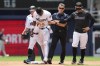 Miami Marlins manager Skip Schumaker, right, helps Jazz Chisholm Jr., second from left, after he was injured attempting to steal second base during the first inning of a baseball game against the Minnesota Twins, Wednesday, April 5, 2023, in Miami. (AP Photo/Lynne Sladky)