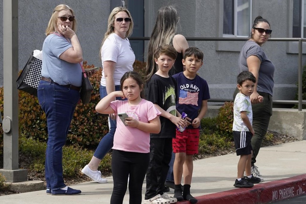 People gather across the street from local fitness center and library where a lockdown occurred in response to a shooting in Roseville, Calif., Thursday, April 6, 2023. Roseville Police say at least three people have been hospitalized.(AP Photo/Rich Pedroncelli)