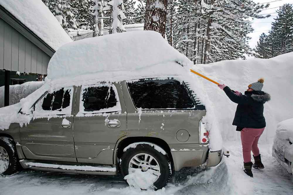 Isabelle Barbosa clears snow off her cars in front of her home along Larch Avenue in South Lake Tahoe, Calif., on Wednesday, March 1, 2023. (Salgu Wissmath/San Francisco Chronicle via AP)