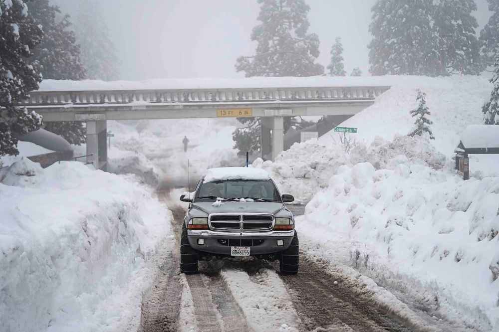 A truck drives along snow berms in Running Springs, Calif., Tuesday, Feb. 28, 2023. Beleaguered Californians got hit again Tuesday as a new winter storm moved into the already drenched and snow-plastered state, with blizzard warnings blanketing the Sierra Nevada and forecasters warning residents that any travel was dangerous. (AP Photo/Jae C. Hong)