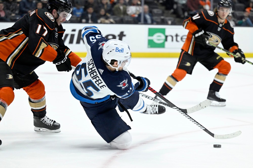 Winnipeg Jets' Mark Scheifele, centre, falls to the ice but still makes a pass with Anaheim Ducks defenceman Scott Harrington, left, defending during the second period. (AP Photo/Alex Gallardo)