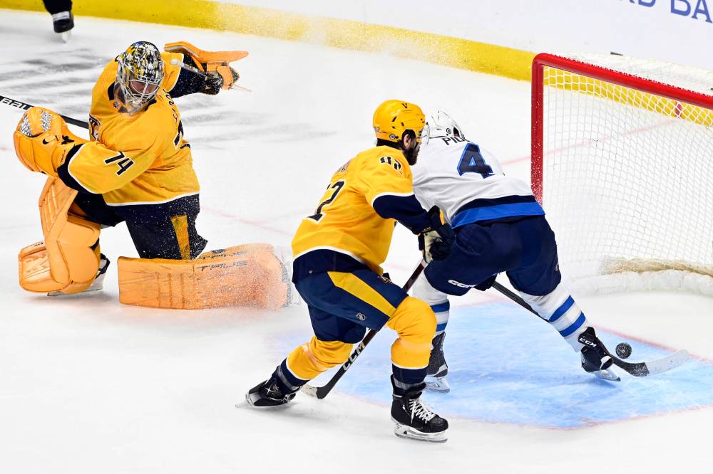 ASSOCIATED PRESS FILES / MARK ZALESKI
Winnipeg Jets defenseman Neal Pionk (4) scores against Nashville Predators goaltender Juuse Saros (74) and center Tommy Novak (82) during overtime on March 18. The Jets won 3-2.