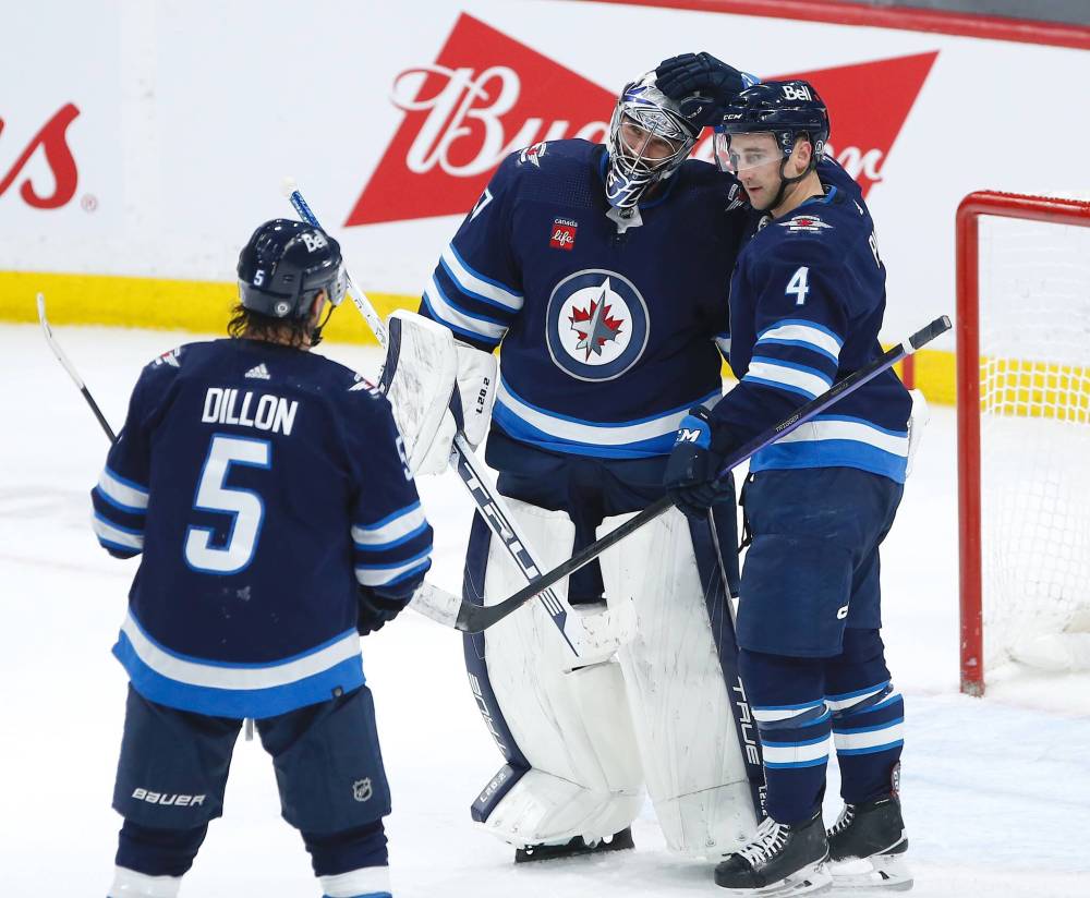 Winnipeg Jets defenceman Neal Pionk, right, celebrates a shutout win over the Nashville Predators with teammates Connor Hellebuyck and Brenden Dillon Saturday. THE CANADIAN PRESS/John Woods