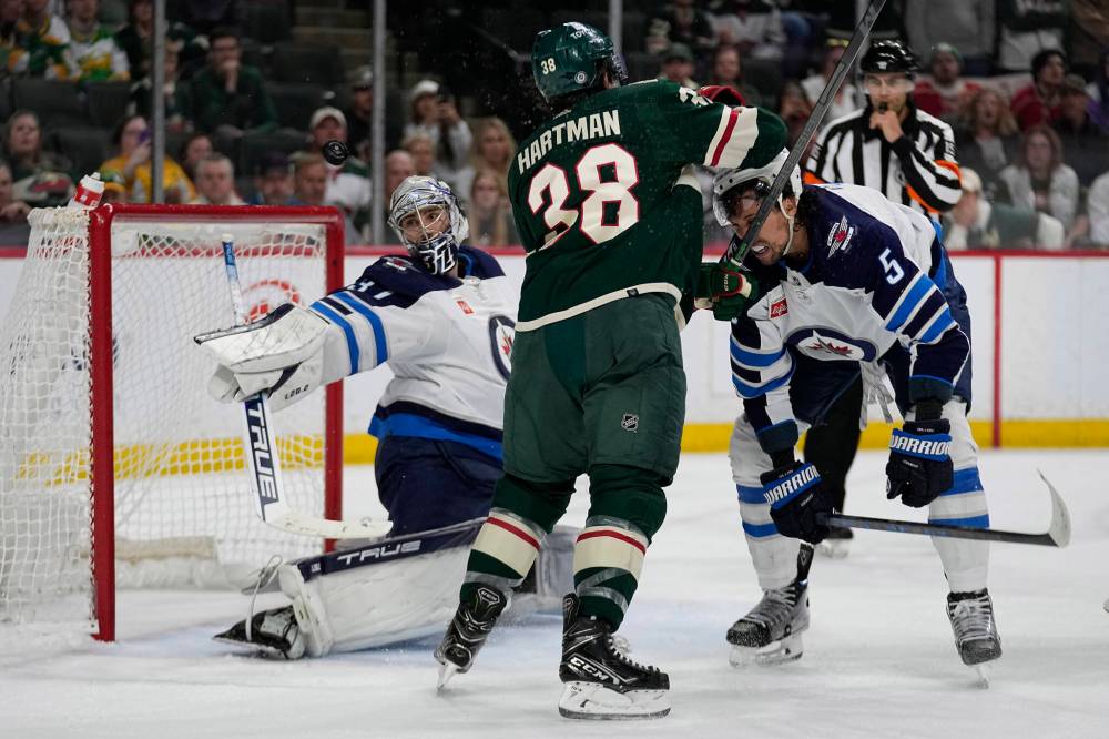 (AP Photo/Abbie Parr)
Winnipeg Jets goaltender Connor Hellebuyck, left, makes a save as Minnesota Wild right wing Ryan Hartman (38) and Winnipeg Jets defenceman Brenden Dillon, right, fight for position during the third period.