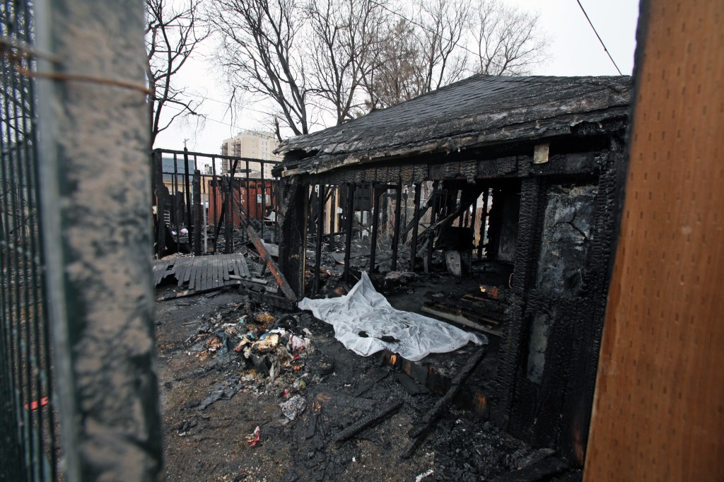 A pair of garages behind two Mountain Avenue homes burned Friday morning. Winnipeg police are investigating after firefighters found a man dead in one of the burnt structures. (Erik Pindera / Winnipeg Free Press)