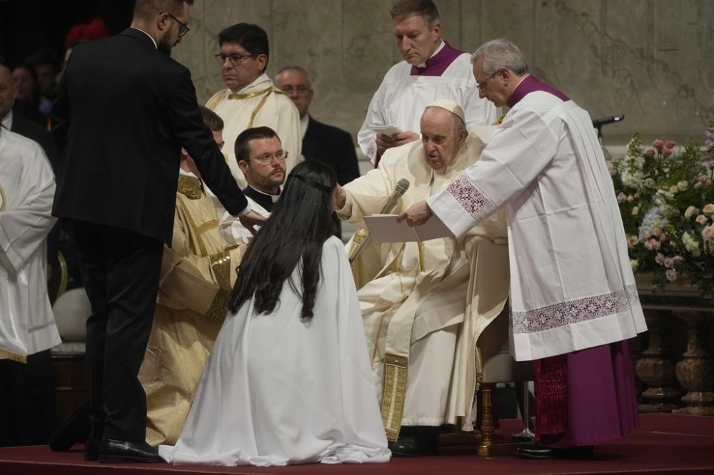 A faithful is baptised by Pope Francis during the Easter vigil ceremony in St. Peter's Basilica at the Vatican, Saturday, April 8, 2023. The service Saturday night in St. Peter's Basilica began in darkness, then dramatically was bathed in light, after a procession up the center aisle by candle-carrying cardinals and other churchmen. (AP Photo/Gregorio Borgia)