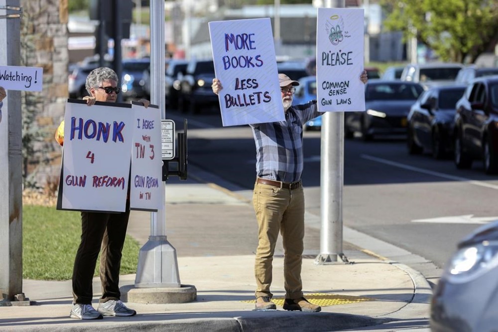 Jean Lusardi, left, and Terry Marek, right, stand on the corners of State Street and Commonwealth Avenue in Bristol, Va., Monday, April 10, 2023, as they show support of gun reform and also of two Black Democrats who were expelled last week from the GOP-led Tennessee House and another legislator who supported them. (Emily Ball/Bristol Herald Courier via AP)