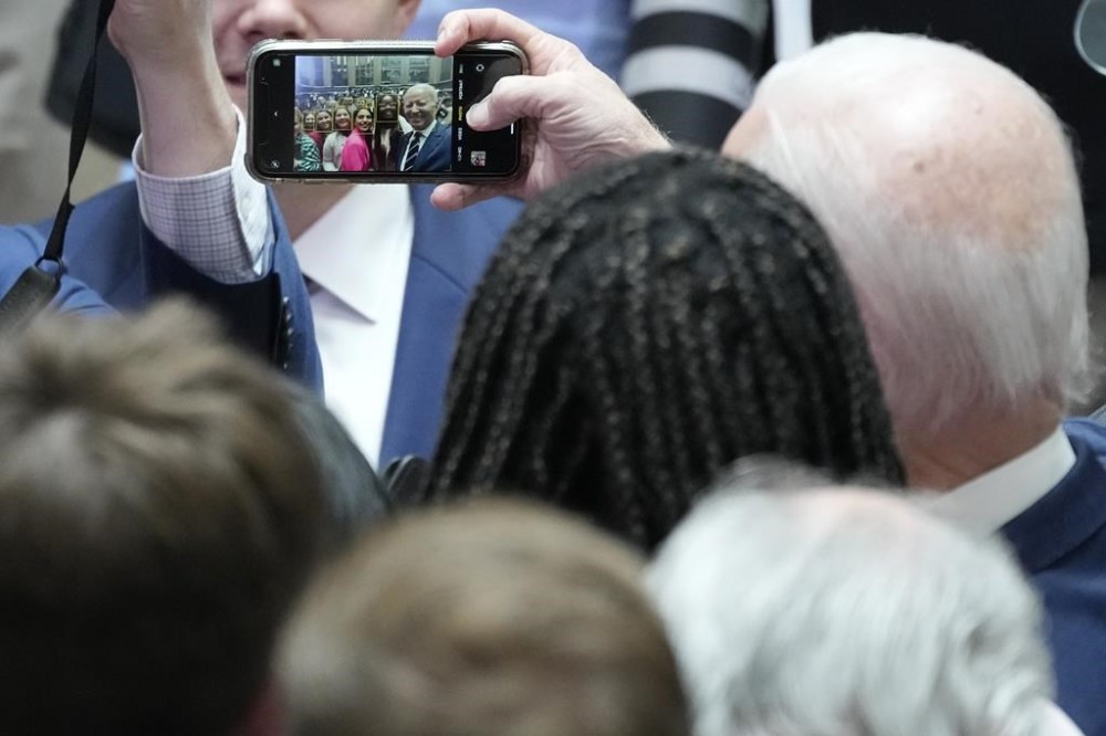 President Joe Biden takes a picture on a cellphone with a member of the audience after making a speech about Northern Ireland's vast economic potential at the Ulster University's new campus in Belfast, Northern Ireland, Wednesday, April 12, 2023. President Biden is in Northern Ireland on Wednesday to participate in marking the 25th anniversary of the Good Friday Agreement, which brought peace to this part of the United Kingdom, as a new political crisis tests the strength of that peace.(AP Photo/Christophe Ena)