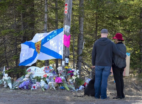 A couple pays their respects at a roadblock in Portapique, N.S. in April 2020. (Andrew Vaughan / The Canadian Press files)