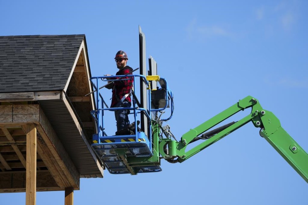 A construction worker works from a lift in a new housing development in Ottawa on Friday, Oct. 14, 2022. An Indigenous-owned investment firm is partnering with the Canada Mortgage and Housing Corporation to build several hundred homes for Indigenous communities. THE CANADIAN PRESS/Sean Kilpatrick