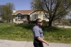 A police officer walks past the house Monday, April 17, 2023, where 16-year-old Ralph Yarl was shot Thursday when he went to the wrong address to pick up his younger brothers in Kansas City, Mo. (AP Photo/Charlie Riedel)