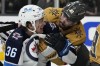 Vegas Golden Knights' Chandler Stephenson (20) helps Winnipeg Jets' Morgan Barron (36) after Barron cut his face on a skate during the first period of Game 1 of an NHL hockey Stanley Cup first-round playoff series Tuesday, April 18, 2023, in Las Vegas. (AP Photo/John Locher)