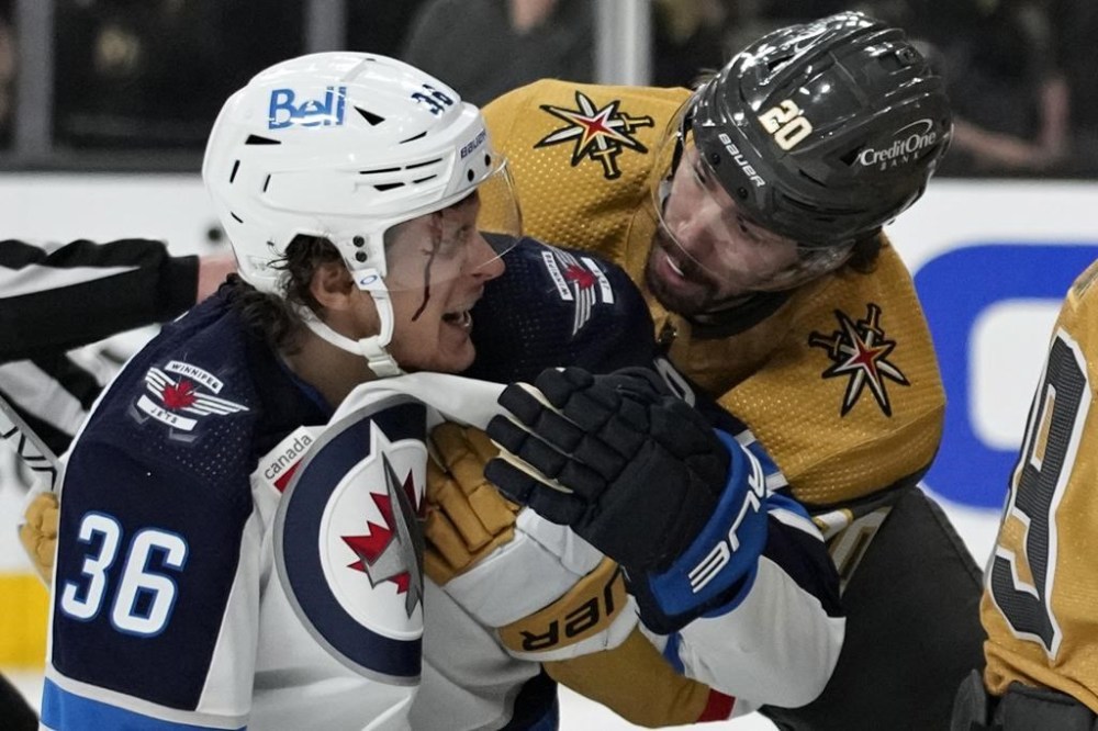 Vegas Golden Knights' Chandler Stephenson (20) helps Winnipeg Jets' Morgan Barron (36) after Barron cut his face on a skate during the first period of Game 1 of an NHL hockey Stanley Cup first-round playoff series Tuesday, April 18, 2023, in Las Vegas. (AP Photo/John Locher)
