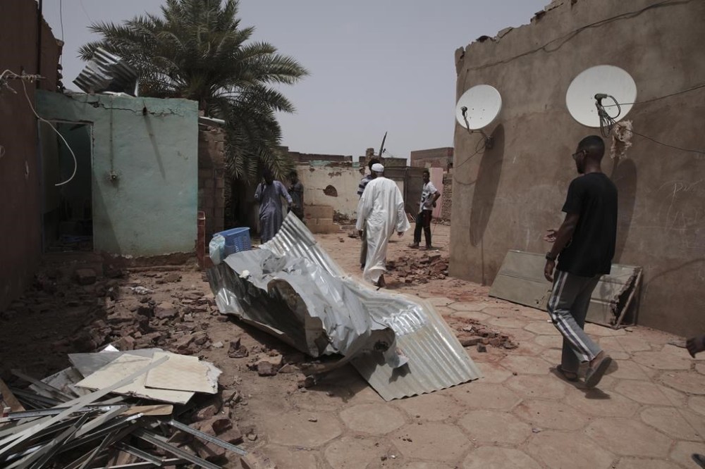 People walk by a house hit in recent fighting in Khartoum, Sudan, Tuesday, April 25, 2023. Sudan's warring generals have pledged to observe a new three-day truce that was brokered by the United States and Saudi Arabia to try to pull Africa's third-largest nation from the abyss. (AP Photo/Marwan Ali)